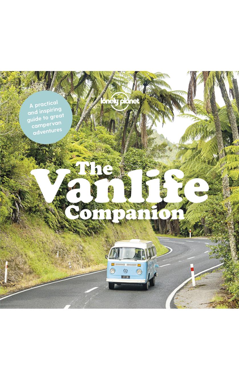 The cover of VANLIFE COMPANION by Brumby Sunstate features a blue and white Volkswagen van on a lush, winding road with palm trees, making it the ideal guide for exploring scenic campervan routes.