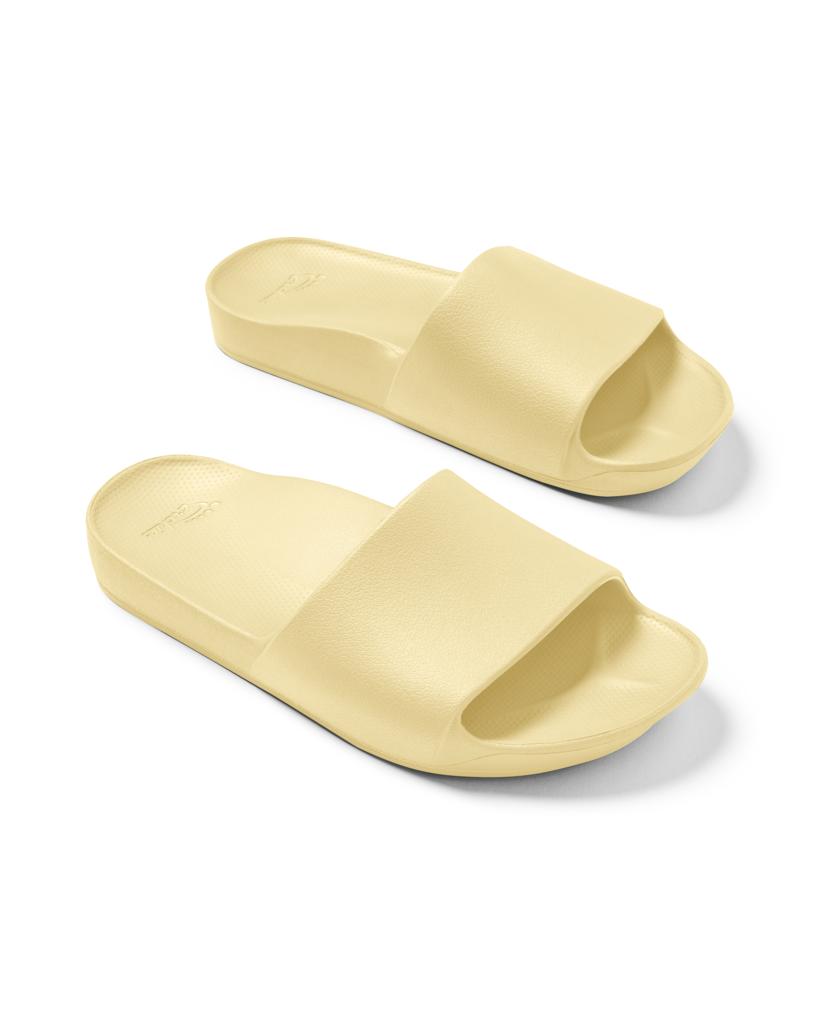 The Archies Archie Slide | Lemon features light yellow, open-toe slides with thick straps and textured soles, made from specialized foam that molds to your foot. Shown on a white background.
