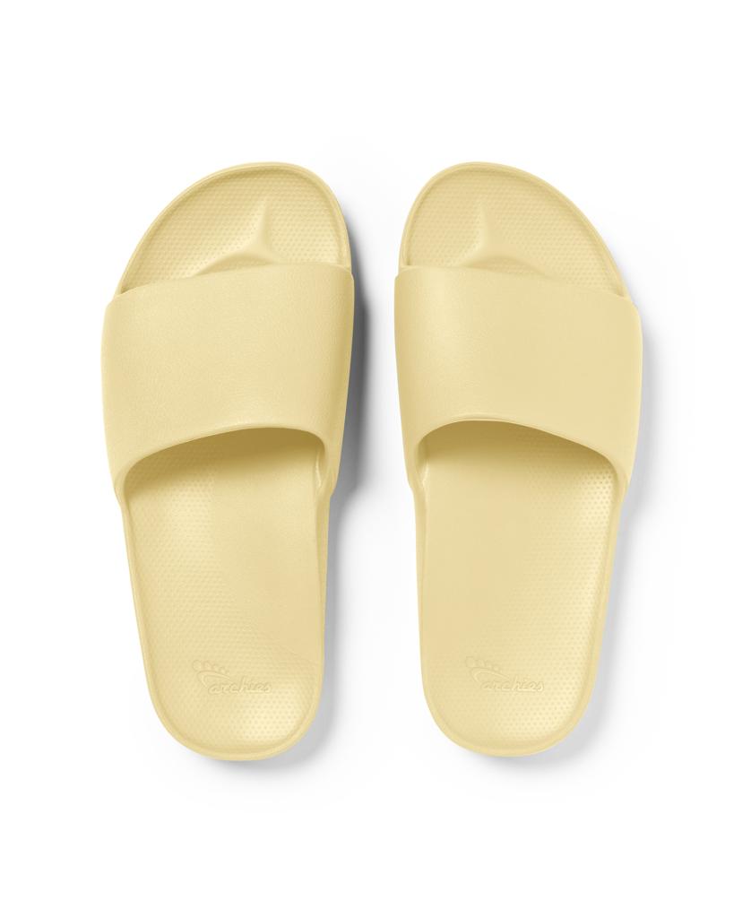 The Archies Archie Slide | Lemon features light yellow arch support slides with wide straps and textured footbeds, made from specialised foam that moulds to your foot, shown from above on a white background.