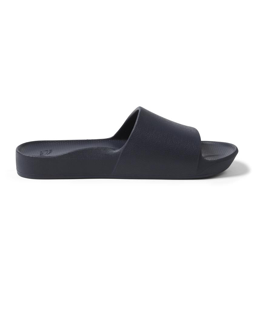 The Archies Archie Slide in Navy is a single slide sandal with arch support, a wide strap, and flat sole made from closed cell foam that molds to your foot, shown in profile on a plain white background.