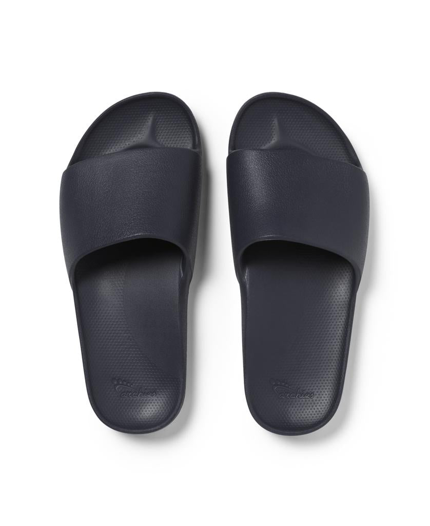 The Archies Archie Slide in Navy is a pair of arch support slides with textured footbeds and wide straps that mould to your feet, shown side by side on a white background.