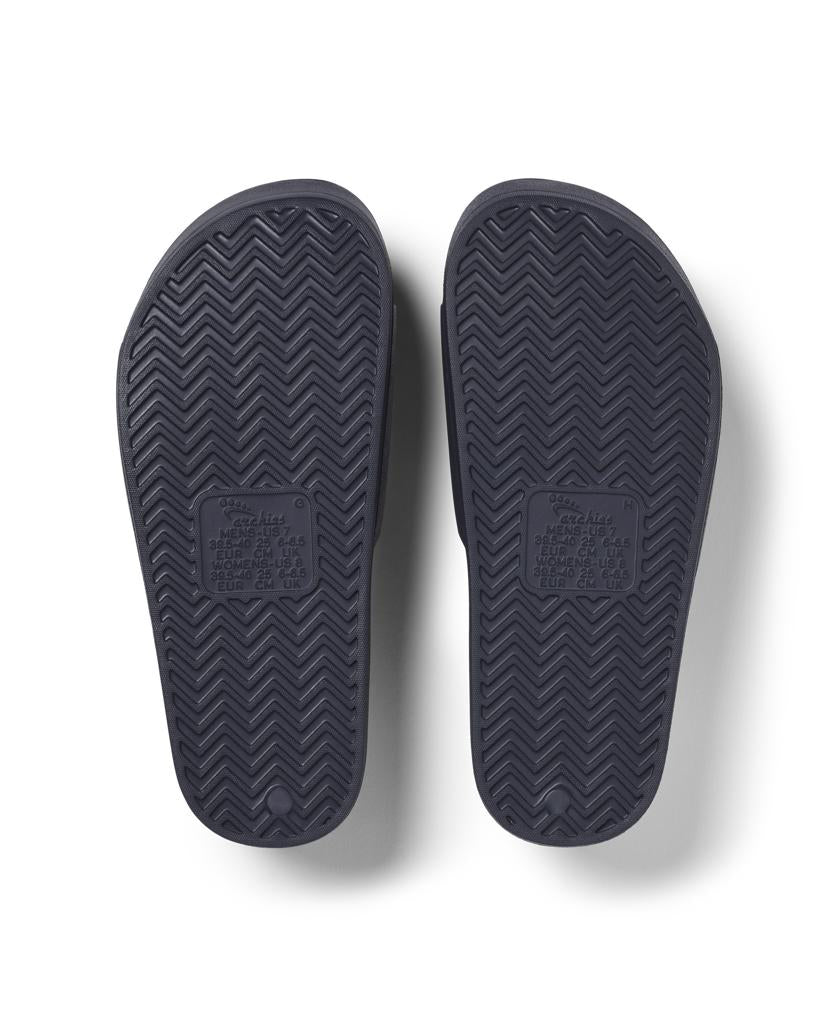 Archies Archie Slide | Navy features dark-colored soles with a chevron tread pattern and a central rectangular label area, made from closed cell foam that molds to your foot for extra comfort.