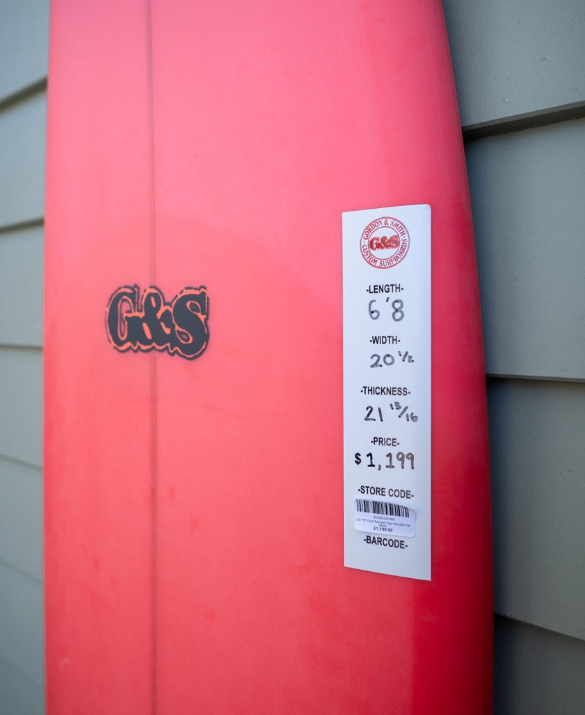 A G&S 68 Cool Tool Mid Twin surfboard by Gordon & Smith in red stands upright against a wall, featuring classic 70s style and a $1,199 price tag—ideal for surfing enthusiasts.