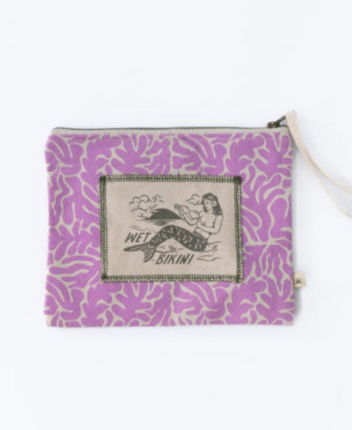 The Bomba WET BIKINI SEAWEED is a purple zippered pouch with a white leaf design and WET BIKINI mermaid patch, featuring a waterproof interior to keep your essentials safe and dry.