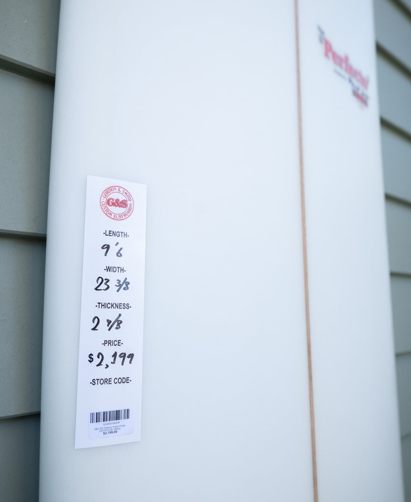 Close-up of a Gordon & Smith G&S 96 Perfecto Polish Finish longboard in white, labeled with 96 x 23 3/8 x 2 1/8, priced at $2,199, mounted on a gray wall—ideal for nose riding.