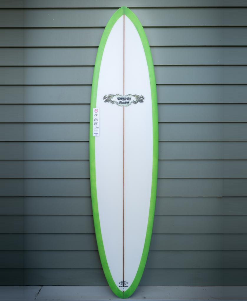 A G&S 74 Magic Polish Finish surfboard in white with a lime border by Gordon & Smith stands upright against a gray paneled wall, channeling the classic Golden Breed Manly style.