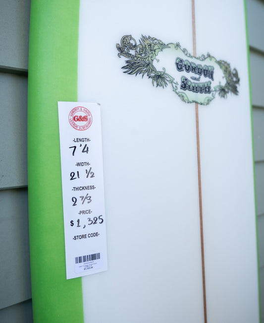 Close-up of a Gordon & Smith G&S 74 Magic Polish Finish surfboard in White/Lime, featuring green edges and product specs: 7’4 length, 21.5 width, 2⅞ thickness. Price: $1,325.