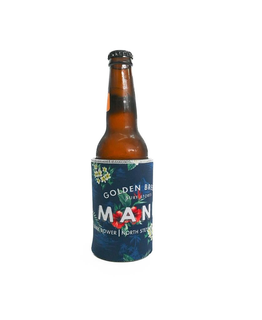 A brown glass beer bottle is held in a Golden Breed Manly Stubby Aloha holder, Dark Navy color, neoprene material, with Golden Brew and Manly Bower North Steyne in sublimated print, set on a plain white background.
