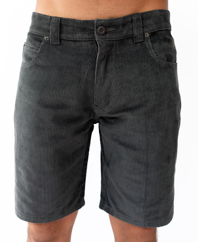 Waist-down view of a person wearing Golden Breeds Floyd Cord Walkshort in Wash Black, featuring 100% cotton corduroy, front pockets, and a structured waist with button closure, shown against a plain white background.