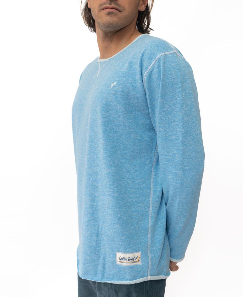 A man in the Golden Breed Classic Rag Top | Sky Marle, a light blue long-sleeve shirt with white stitching, stands against a white background, channeling retro style as he faces slightly to the side.
