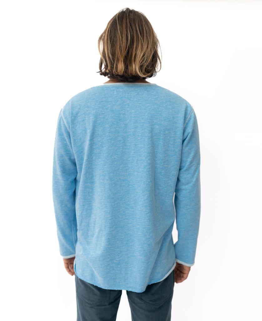 A person with shoulder-length hair faces away, wearing the Golden Breed Classic Rag Top in Sky Marle and dark pants, embracing a subtle retro vibe against a plain white background.