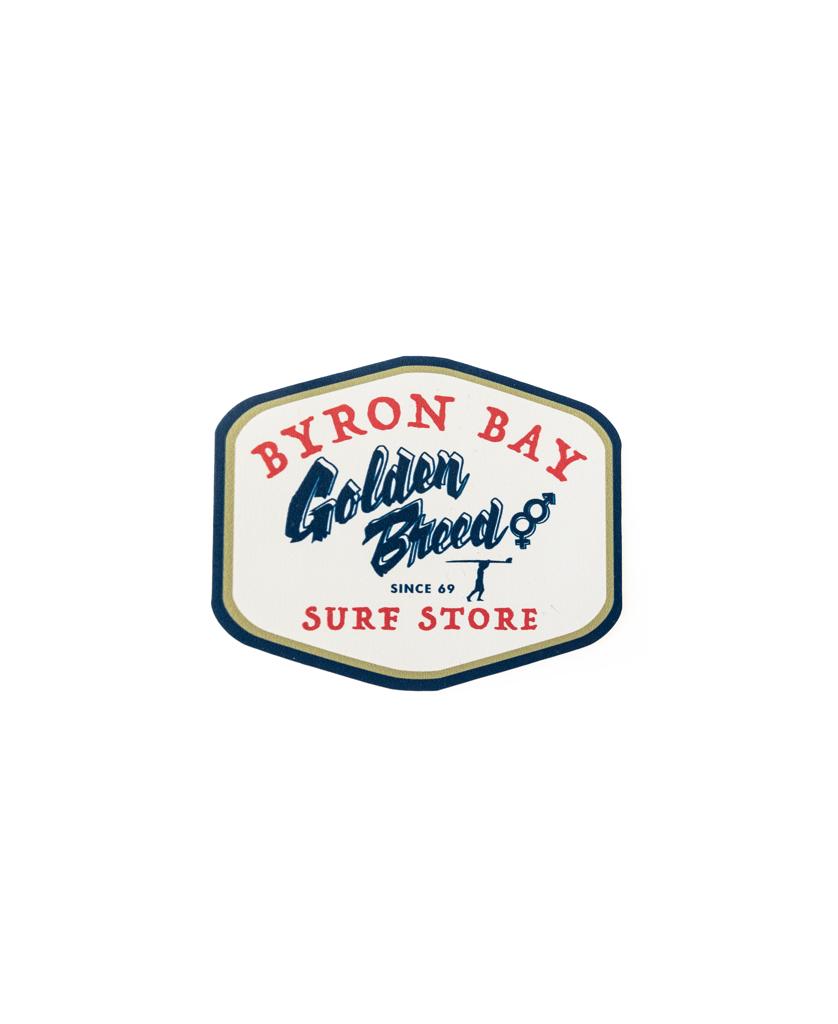 The Golden Breed GB Byron Al Sticker | Cream features a badge-shaped logo with Byron Bay Golden Breed Since 69 Sure Store in red and blue on white—a quality Australian-made sticker perfect for showing Byron pride.
