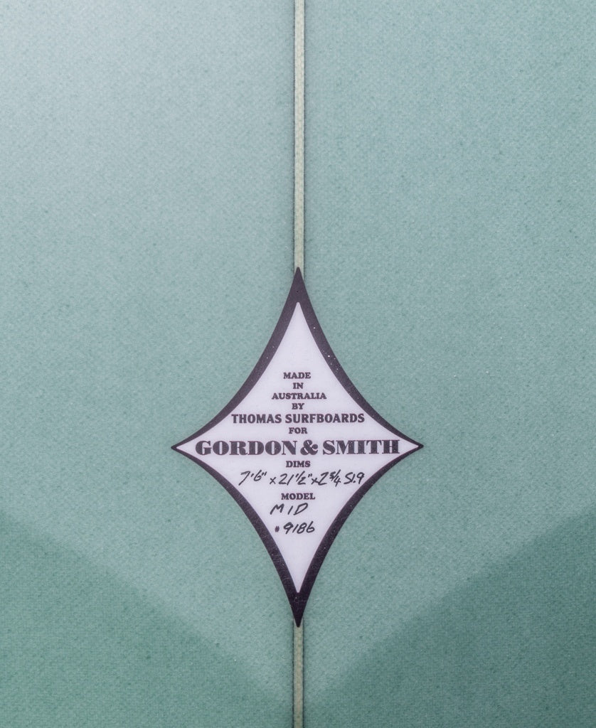 Diamond-shaped label on the G&S Mid length Malachite Green 76 surfboard features dimensions, model, and Gordon & Smith branding. Ideal all-rounder for versatile wave conditions.