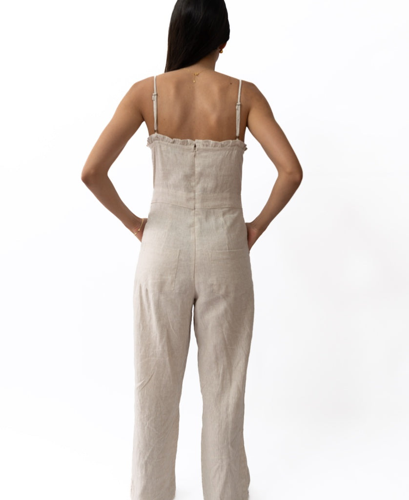 A woman is seen from the back wearing the Lazy Beach Emmy Overall in Natural, featuring adjustable straps and an Australian design, against a plain white background.