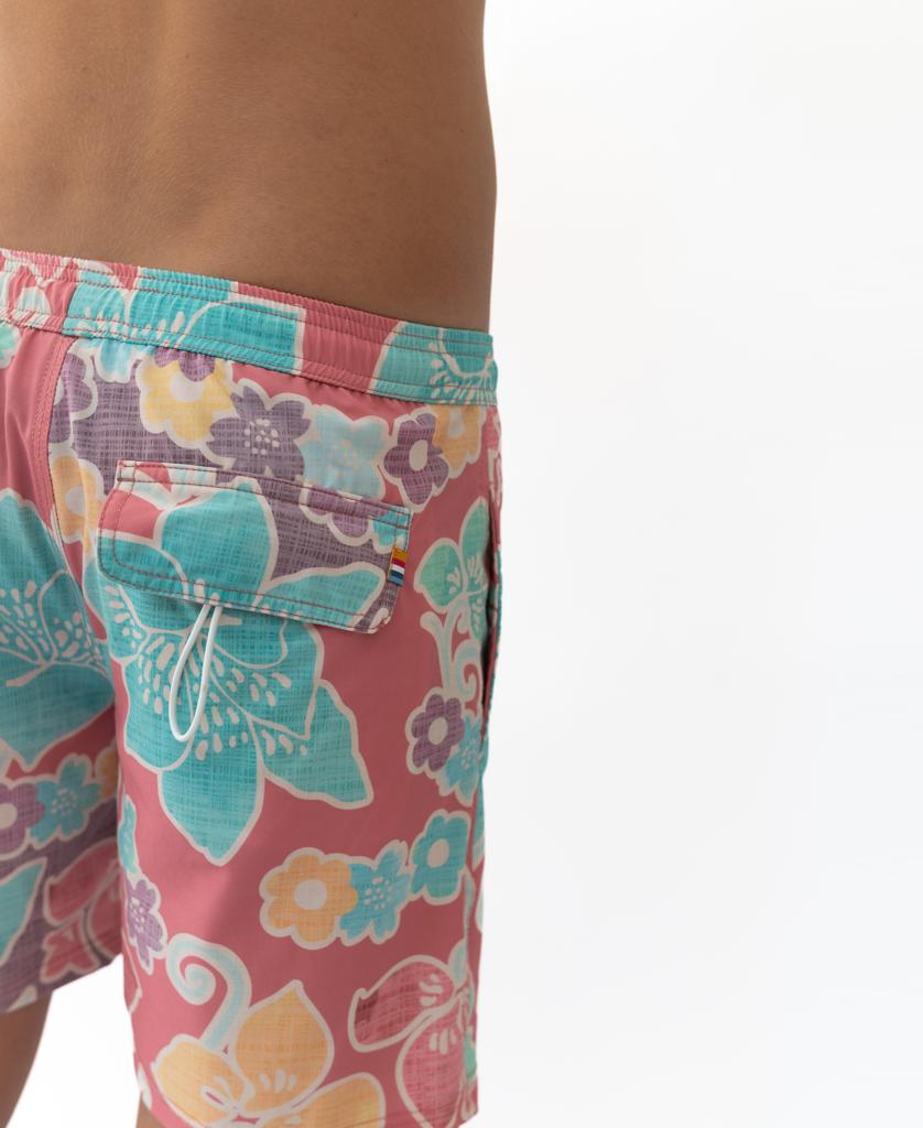 A person wearing Golden Breed’s Batik Elastic Waist Boardie in Rose, featuring a pink floral design and made from recycled polyester, shown waist down against a white background.