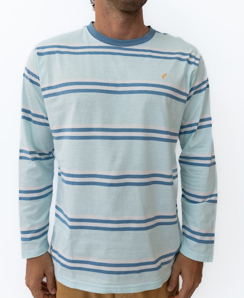 A person wearing the Golden Breed Bay Stripe LS Tee | Ice—a light blue long-sleeve shirt with white and blue stripes and a small yellow logo on the chest, perfect for that classic Cali surf style.