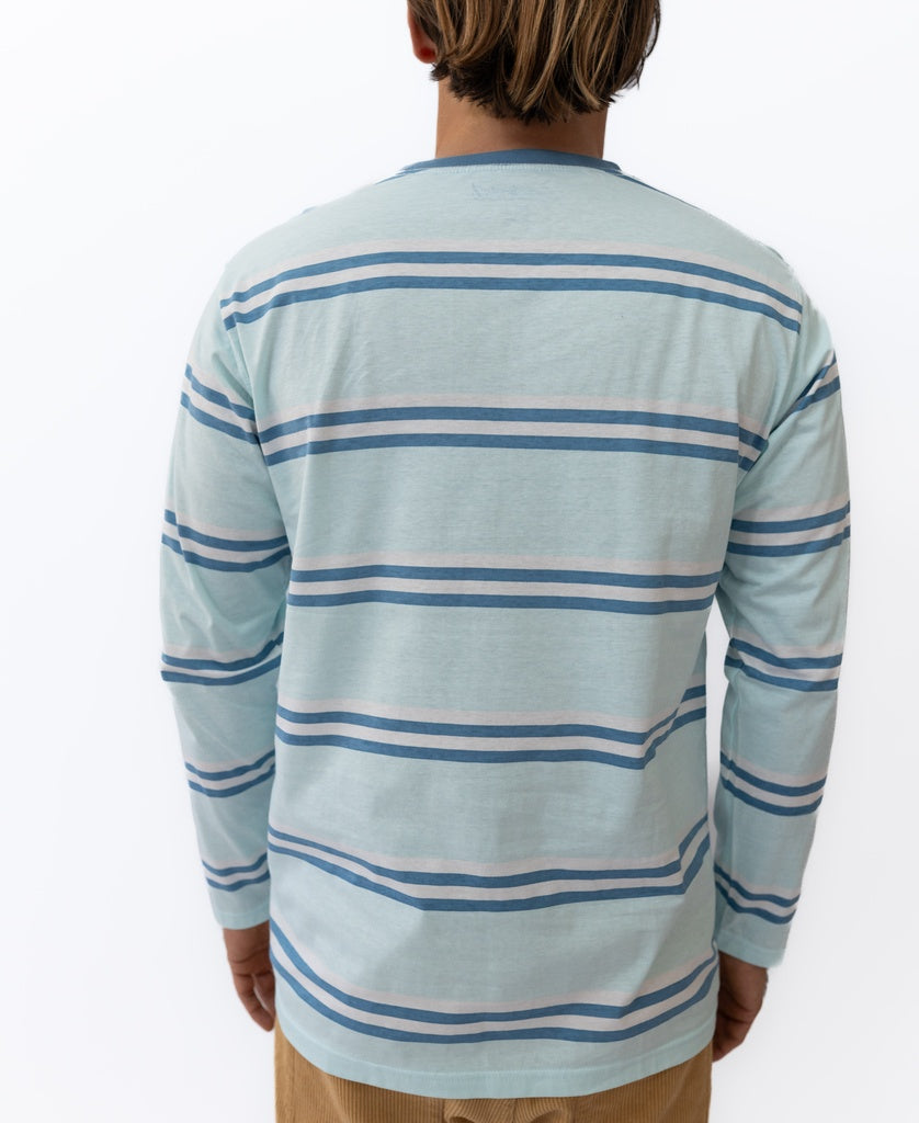A person stands facing away, wearing the Golden Breed Bay Stripe LS Tee | Ice with horizontal navy and white stripes and tan pants, capturing a laid-back Cali surf vibe against a white background.