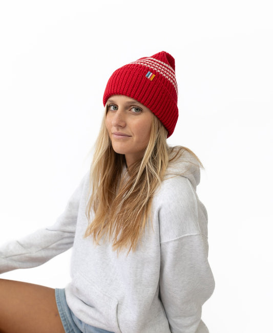 A woman with long blonde hair wears the Golden Breed Beach Boy Wool Beanie in red and a light gray hoodie, sitting against a plain white background.