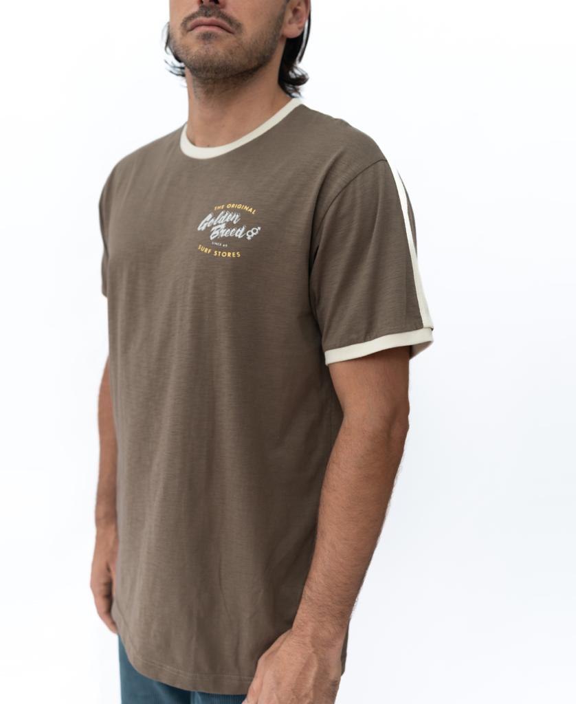 Man wearing the Golden Breed Break Ringer Tee in Wash Brown, a 100% cotton short-sleeve t-shirt with white trim and small left chest text graphic, standing against a plain white background.