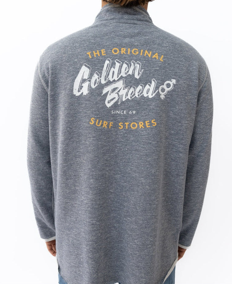 A person wears a navy marle Golden Breed Break 1/4 Zip Rag Top featuring “The Original Golden Breed Surf Stores Since 69” in white and yellow on the back, crafted from soft French Terry for extra comfort.