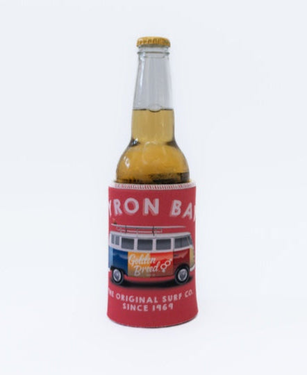 A brown glass bottle in a red Byron Stubby Kombi | Wash Red holder by Golden Breed, made from neoprene, featuring a vibrant van design and the text “BYRON BAY” and “The Original Surf Co. Since 1969.”.