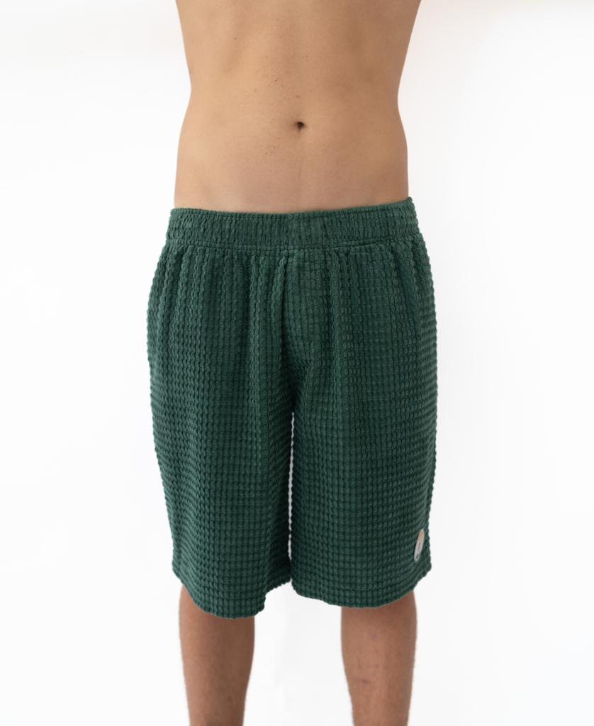 A person models the Golden Breed El Solito Walkshort in Ivy Green, made from chunky cotton cord, standing against a white background with only the shorts and lower body clearly visible.