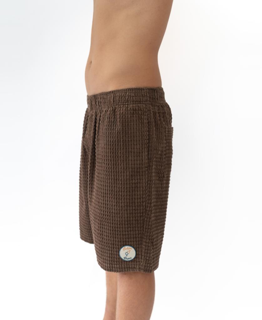 A person is shown from the waist down wearing Golden Breed El Solito Walkshort in Wash Brown with a small circular patch near the hem, standing out against a plain white background.