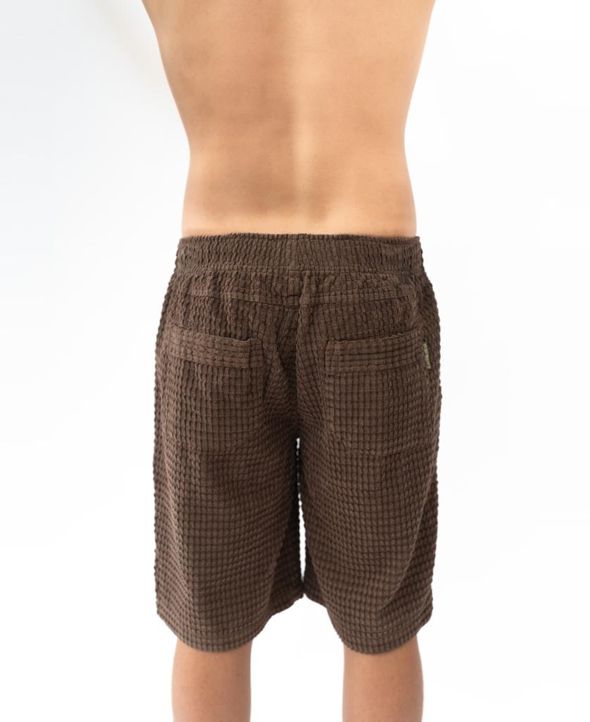 A person shown from the back, wearing Golden Breed’s El Solito Walkshort in Wash Brown, stands against a plain white background.