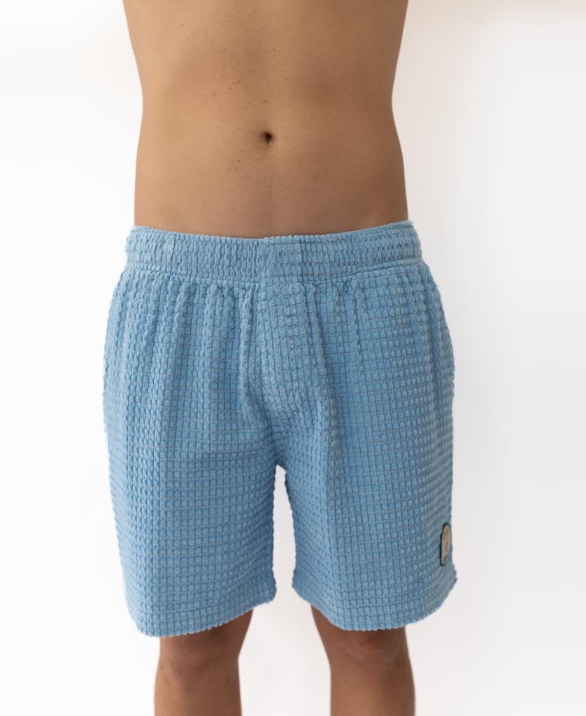 A person wears Golden Breeds El Shorto Walkshort in Azure Blue, shown from mid-chest to thighs against a plain white background.