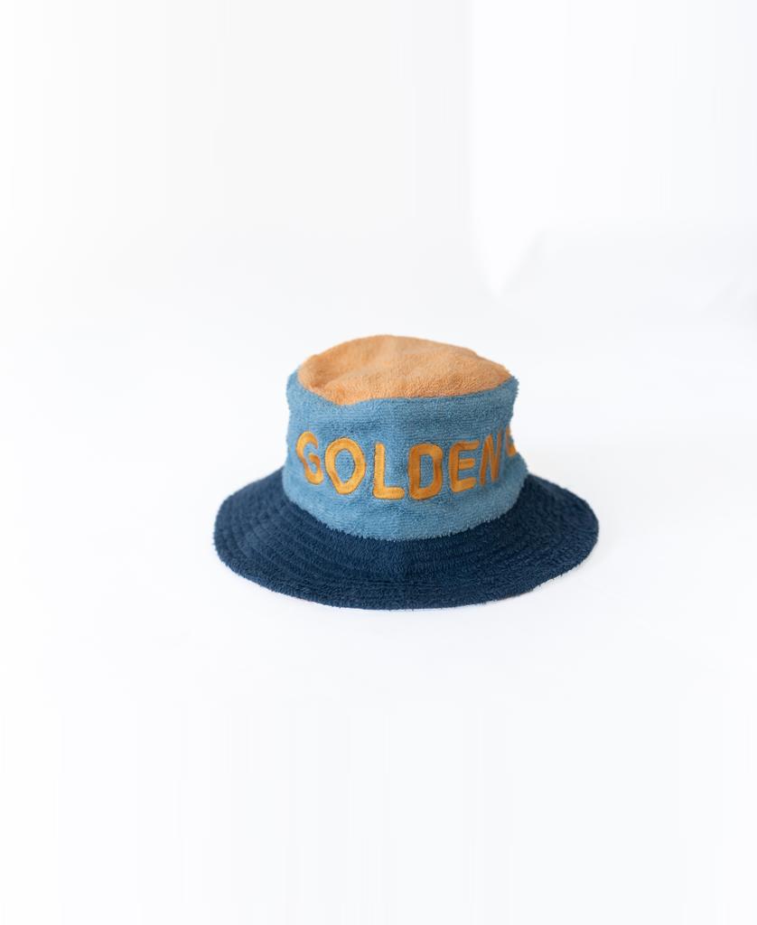 The Ferry Terry Bucket Hat in Azure Blue by Golden Breed features GOLDEN embroidered in yellow on the front, inspired by the brand’s classic style.