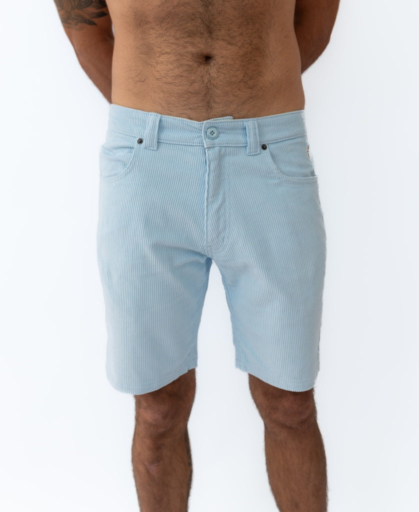 A man wears Golden Breed Floyd Cord Walkshort in Sky, light blue, standing against a white background, shown from waist to knees.