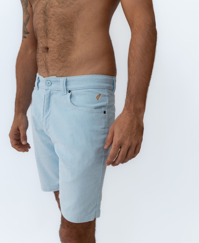 A man wearing Golden Breed Floyd Cord Walkshort in Sky stands against a plain white background, shown from mid-chest to knee.