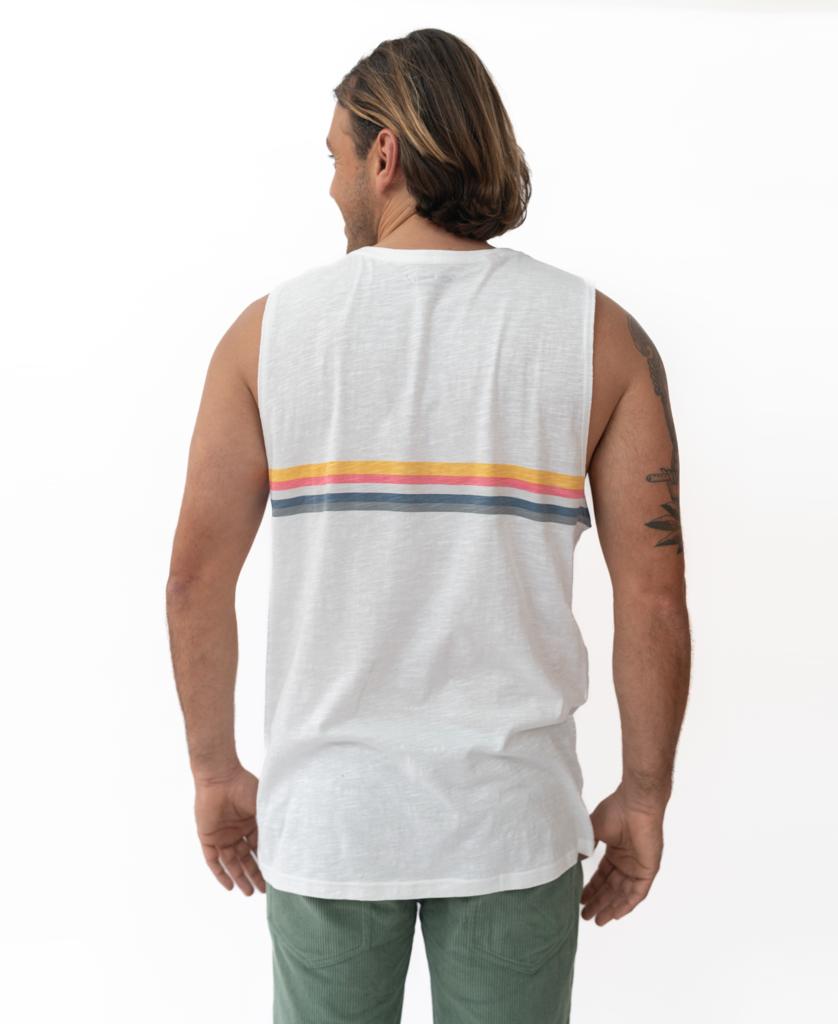 A man with shoulder-length hair wears the GoJo Muscle Tank in Off White by Golden Breed, featuring horizontal stripes and green pants, channeling 70s style as he stands with his back to the camera.