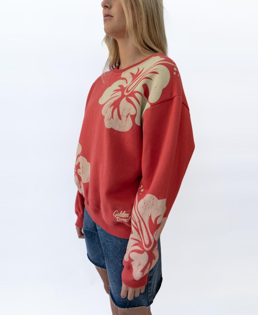 A person wears the Golden Breed Hibiscus Sweat in Wash Red/Beige—a 100% cotton fleece sweatshirt with bold beige floral prints—paired with denim shorts, standing against a plain white background.