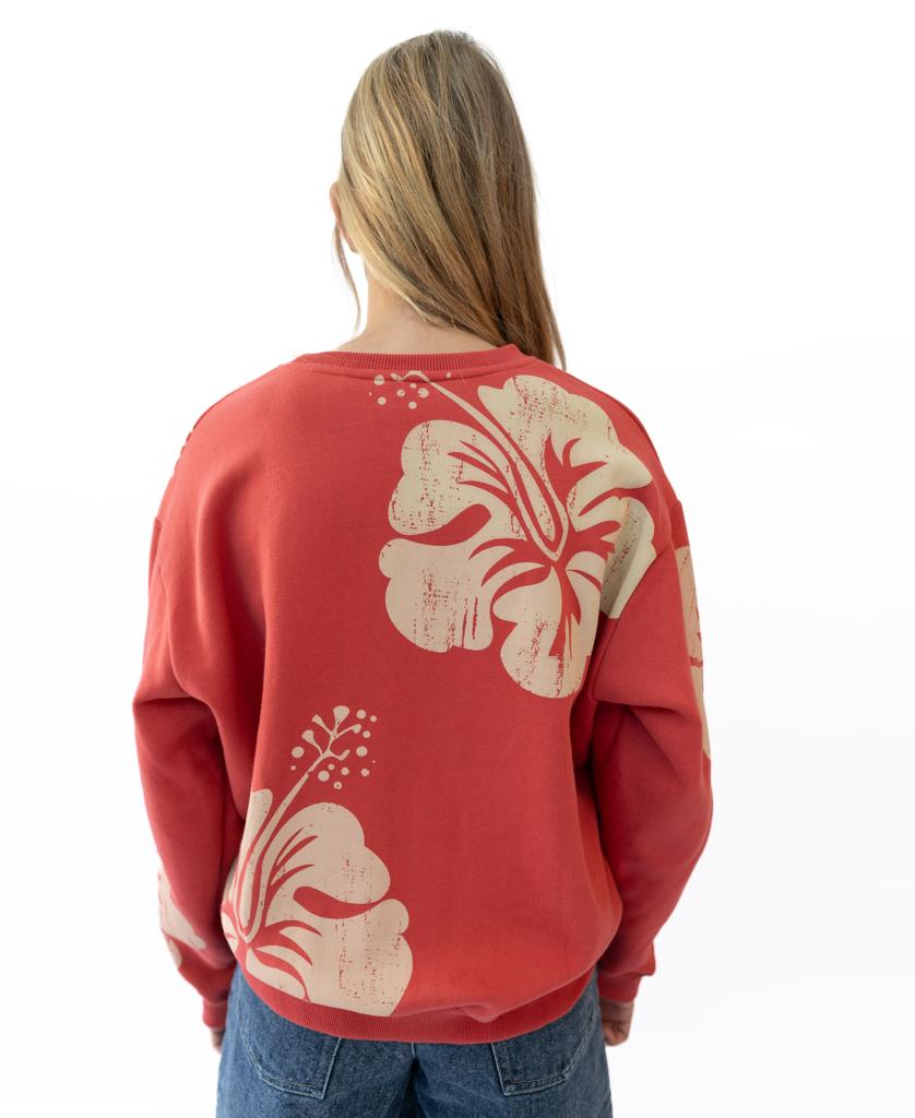 A person faces away from the camera in a white setting, wearing the Golden Breed Hibiscus Sweat in wash red/beige—a cozy 100% cotton fleece sweatshirt with bold beige floral prints on the back.