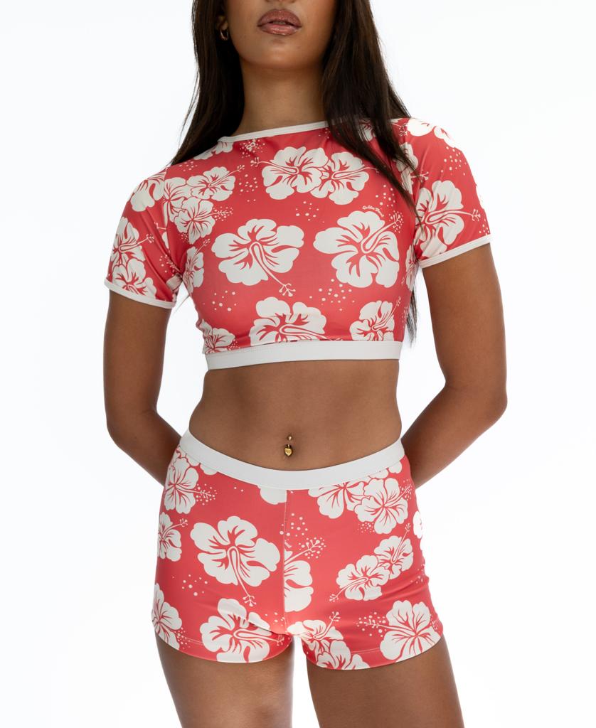 A woman wears the Golden Breed Indie Crop Tee in Hibiscus Wash Red/Beige, a matching eco-friendly set made from recycled fabric, standing against a plain white background.