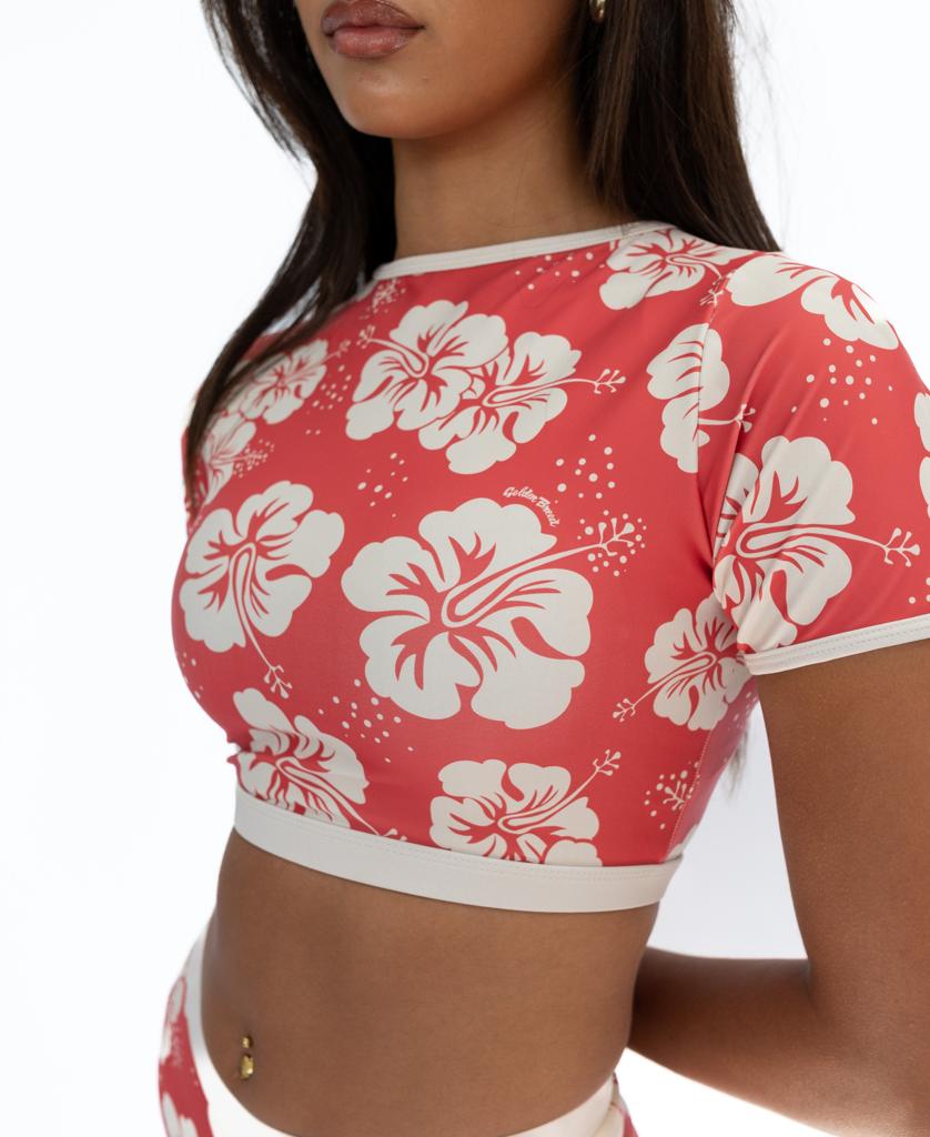 A woman models the Golden Breed Indie Crop Tee in Hibiscus Wash Red/Beige, a short-sleeve floral top crafted from eco-friendly recycled fabric, against a plain white background.
