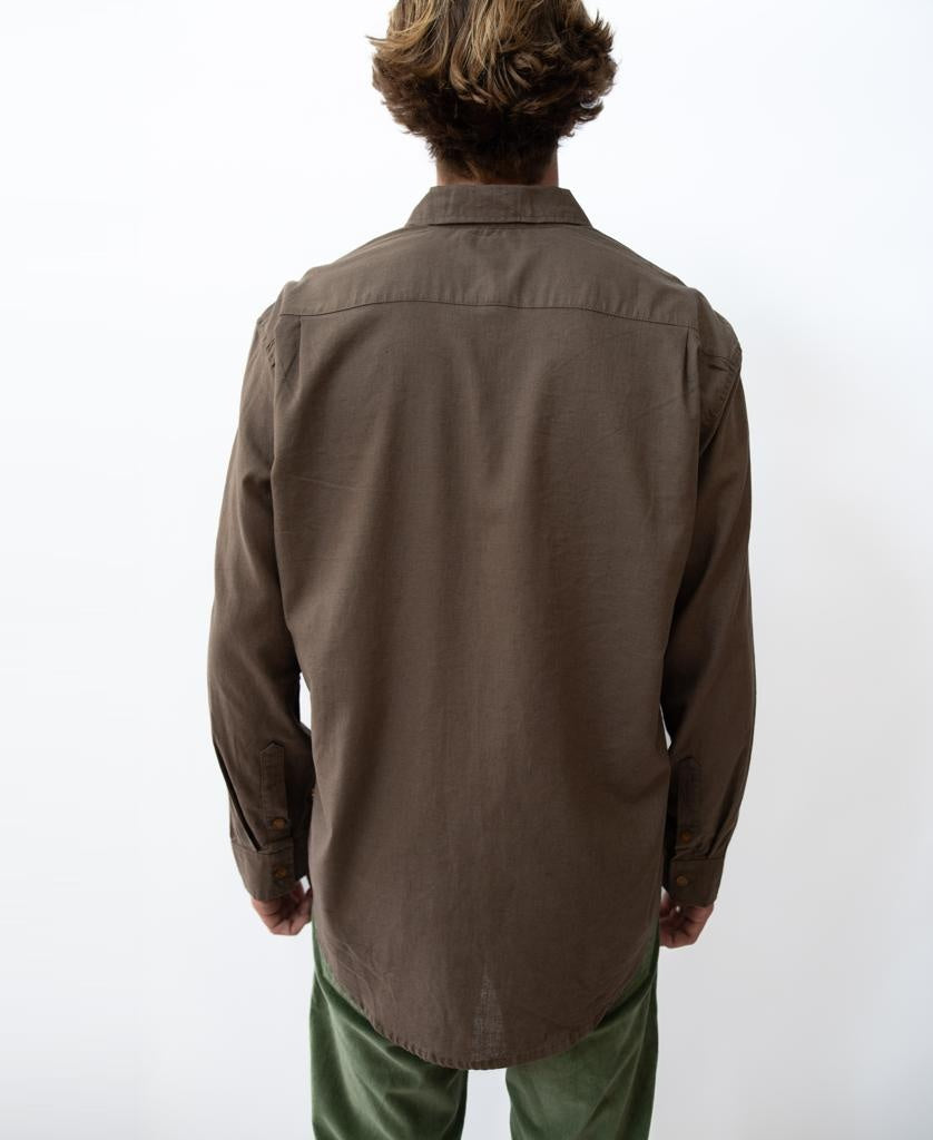 A person stands with their back to the camera, wearing the Golden Breed Linen LS Shirt in Wash Brown and green pants against a plain white background.