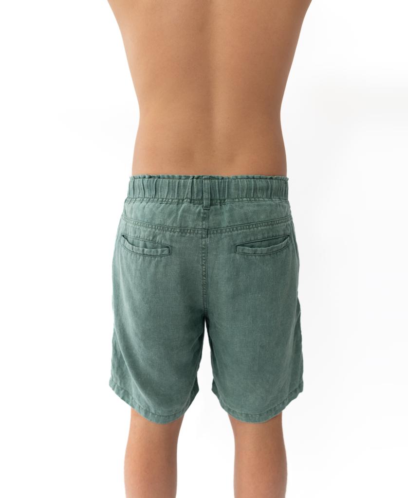 A person stands with their back to the camera, wearing Golden Breeds Linen Short in Khaki with an elastic waist and no shirt, set against a white background.