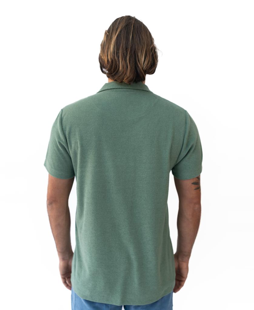 A person with shoulder-length hair, wearing the Golden Breed Vintage Long Island Polo in Khaki and blue pants, stands with their back to the camera against a white background.