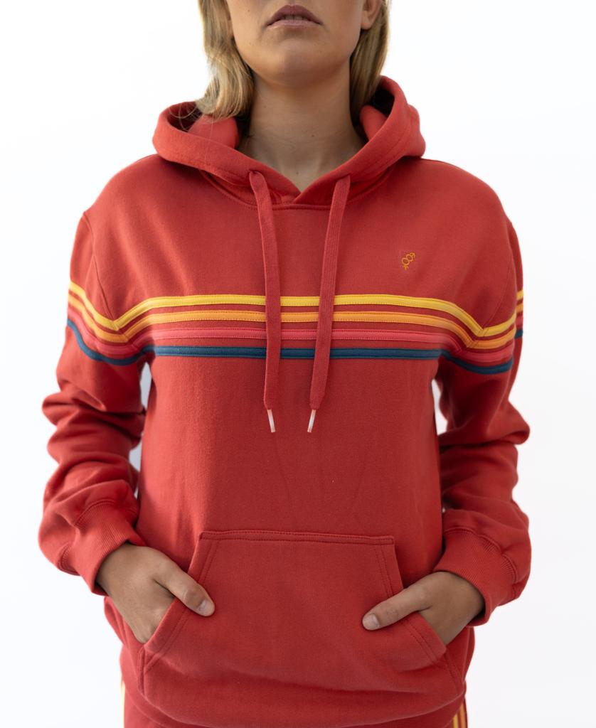 A person wears the Golden Breed Long Island Hoodie | Wash Red, made from 100% cotton fleece, featuring yellow and blue horizontal stripes on a red background, while standing against a plain white backdrop.