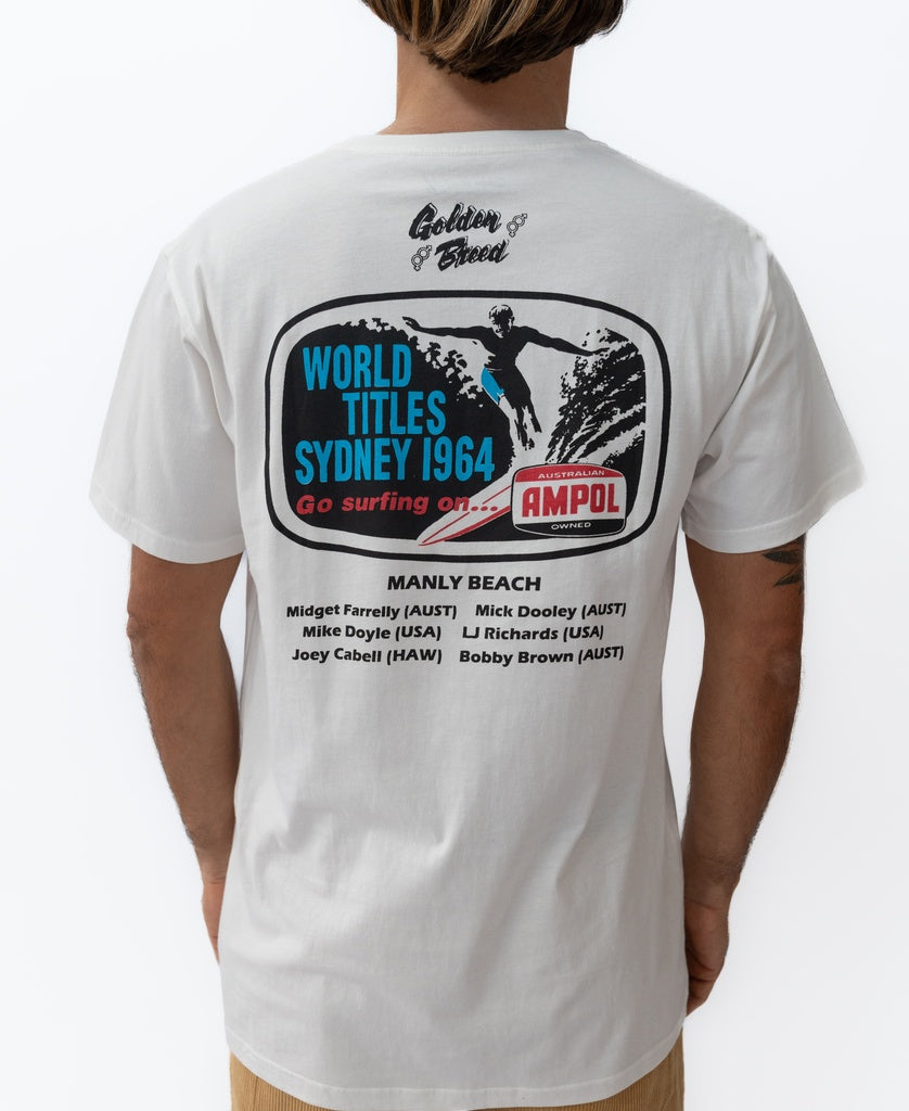 A person wears the Golden Breed Manly Ampol Tee in Off White, featuring a back graphic referencing the 1964 Ampol World Surf Championships at Manly Beach, Sydney, with surfer names and sponsors.