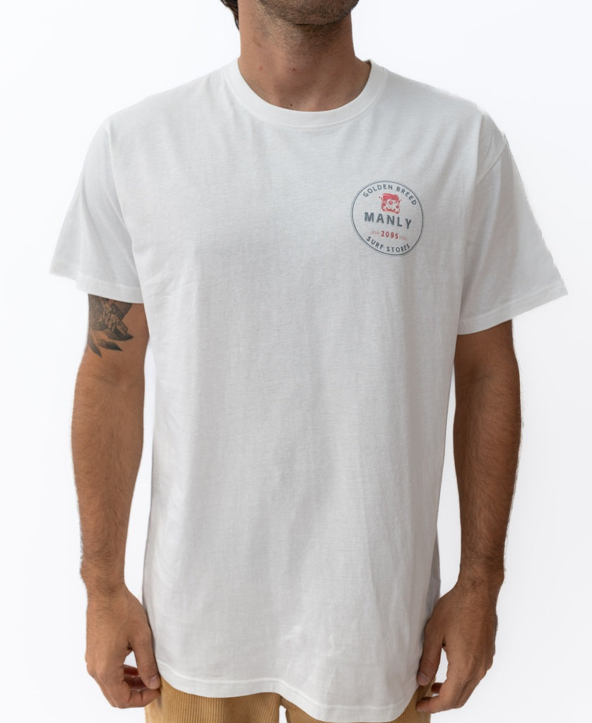 A man wears the Golden Breed Manly Kombi Tee in off white, featuring a classic fit and a small circular logo on the left chest that reads Golden Breed Manly 1969 Surf Store.