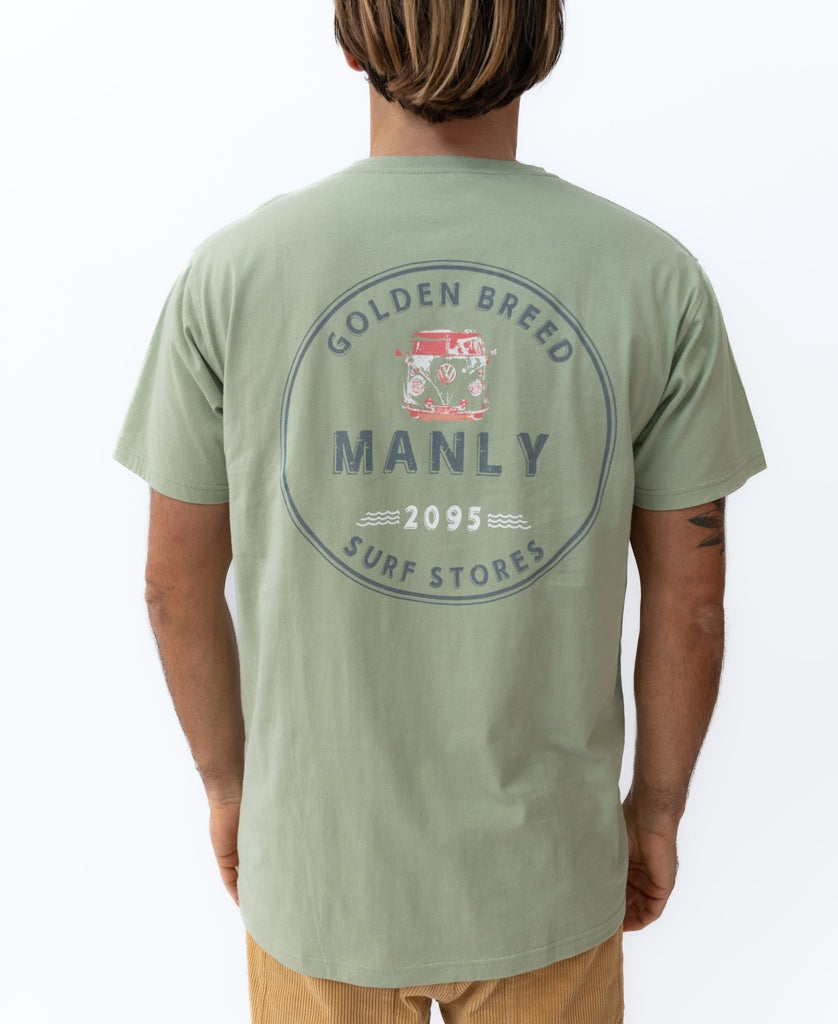 Wearing the Golden Breed Manly Kombi Tee in Sage, featuring a circular Manly Surf Stores 2095 logo and red van graphic on the back—100% cotton and perfect for that laid-back surf town vibe.
