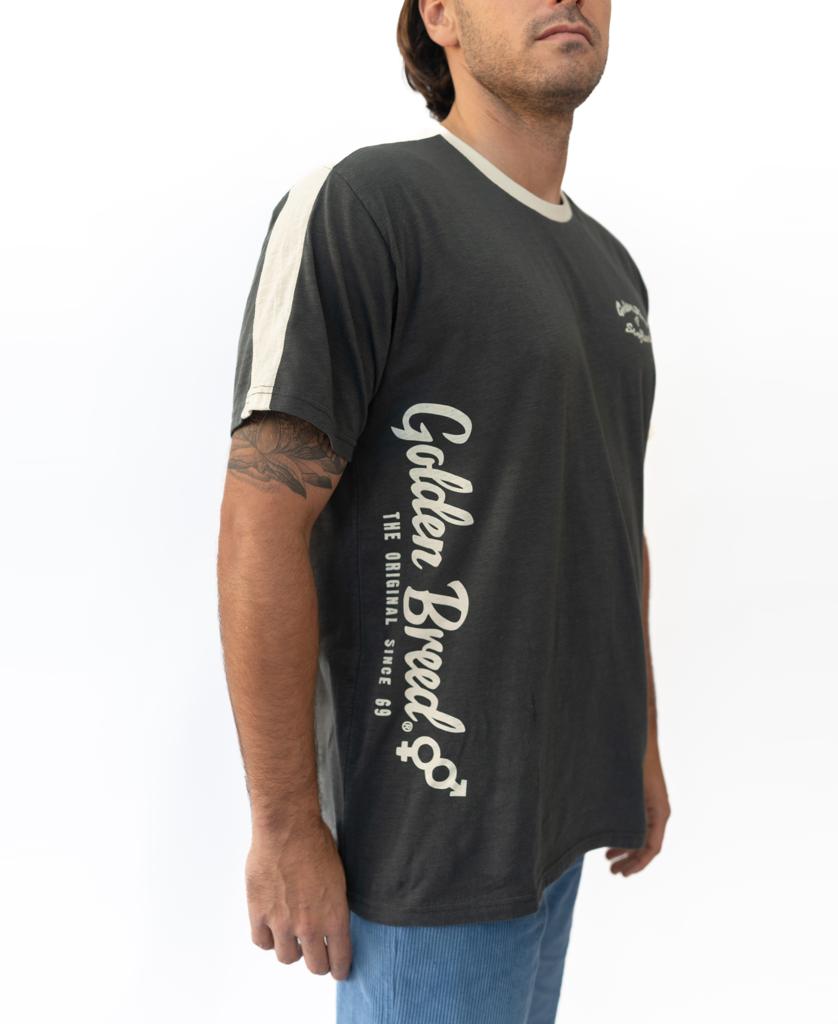 A man wears the Wash Black Mitch Tee by Golden Breed, crafted from soft cotton slub with white trim and vertical Golden Breed text, standing against a plain white background.