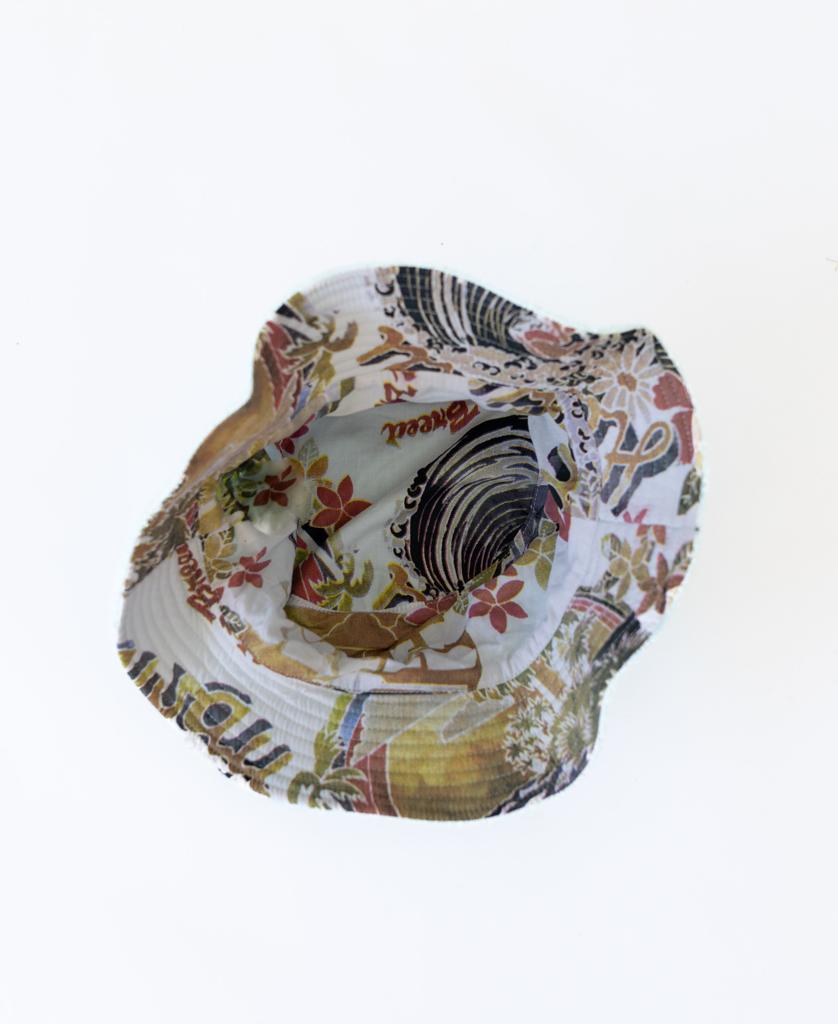 A top view of the Golden Breed Norris Terry Bucket Hat | Sky, showcasing colorful floral and abstract patterns on soft terry towelling, set against a white background.