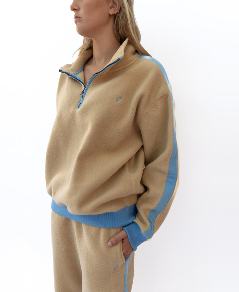 A woman models the Golden Breed Peggy 1/2 Zip Retro tracksuit in Beige/Azure, featuring blue trim and a vintage sweat collar, standing against a white background.