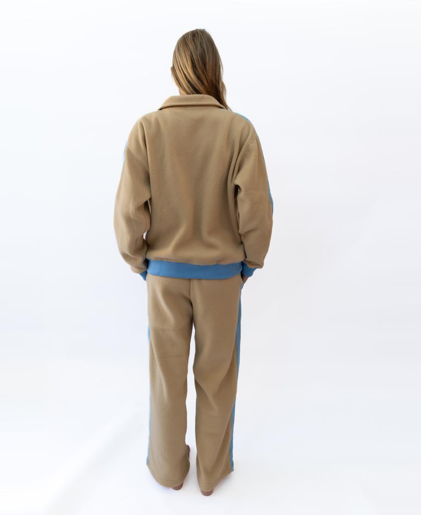 A person stands with their back to the camera, wearing the Golden Breed Peggy 1/2 Zip Retro fleece jacket in Beige/Azure, featuring subtle retro zip details and light blue trim, against a plain white background.