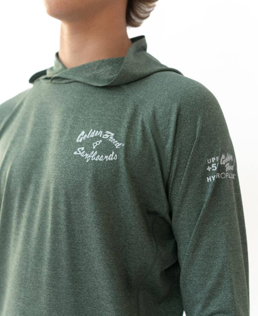 A person wearing the Golden Breed Rapper Hoodie Rash Shirt in green marle, featuring 50+ UPF HYROFLX and Golden State Surfboards printed in white—perfect for any surf session.