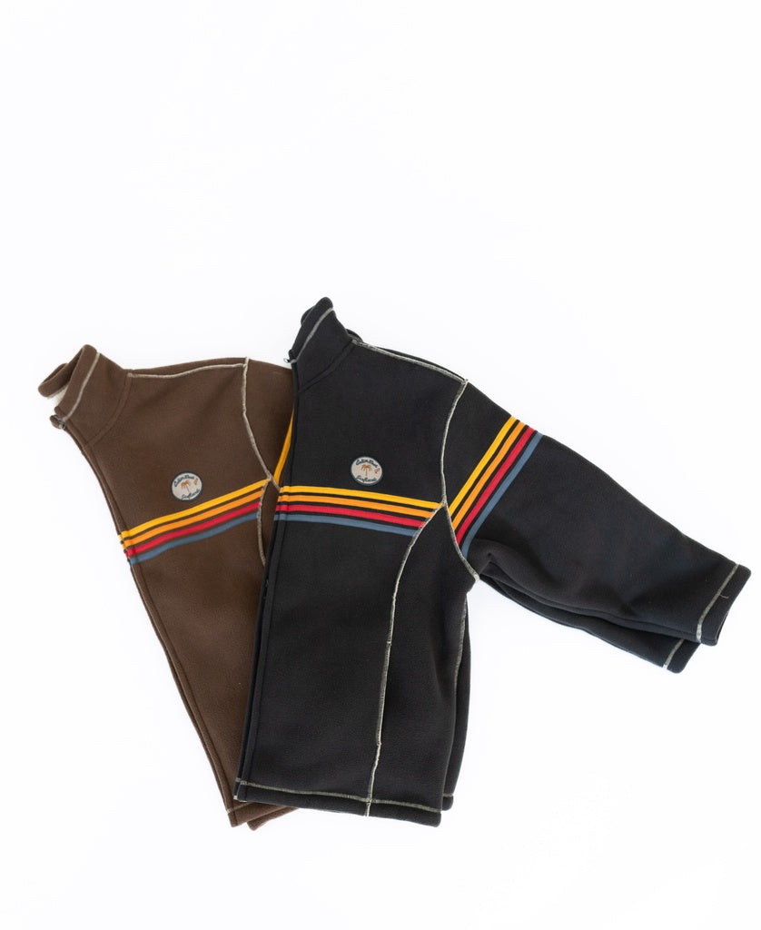 Two Reef Bonded Sherpa Jackets by Golden Breed—one brown, one black—feature multicolored stripes and a patch. Made from soft polyester sherpa, they offer comfort and vibrant style, shown laid flat on a white background.